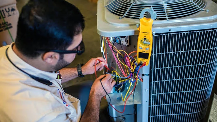 Technician testing air-conditioning wiring with a yellow electrical meter