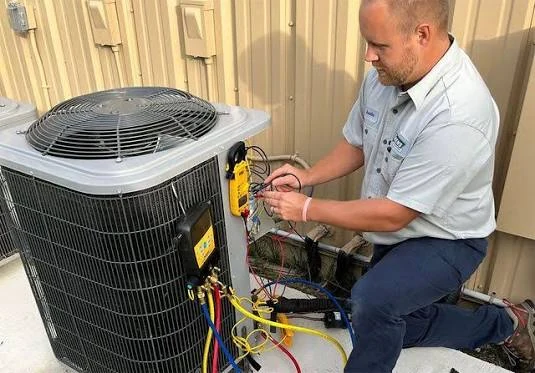 Technician measuring system operation beside a residential condenser