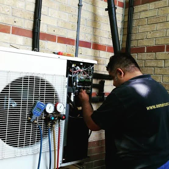 Technician inspecting the open service panel of an outdoor air-conditioning unit