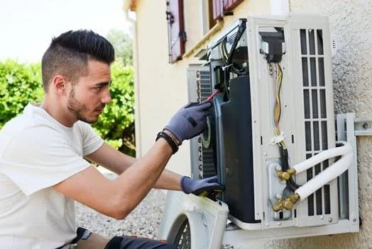 Technician inspecting the service compartment of a wall-mounted outdoor unit