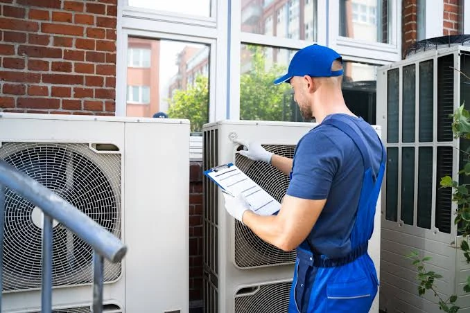 Technician with a clipboard checking outdoor heating and cooling equipment