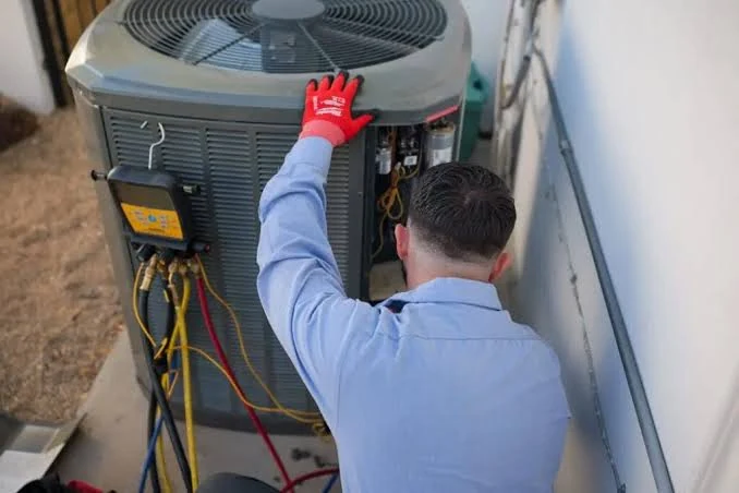 Technician inspecting a condenser beside a home exterior